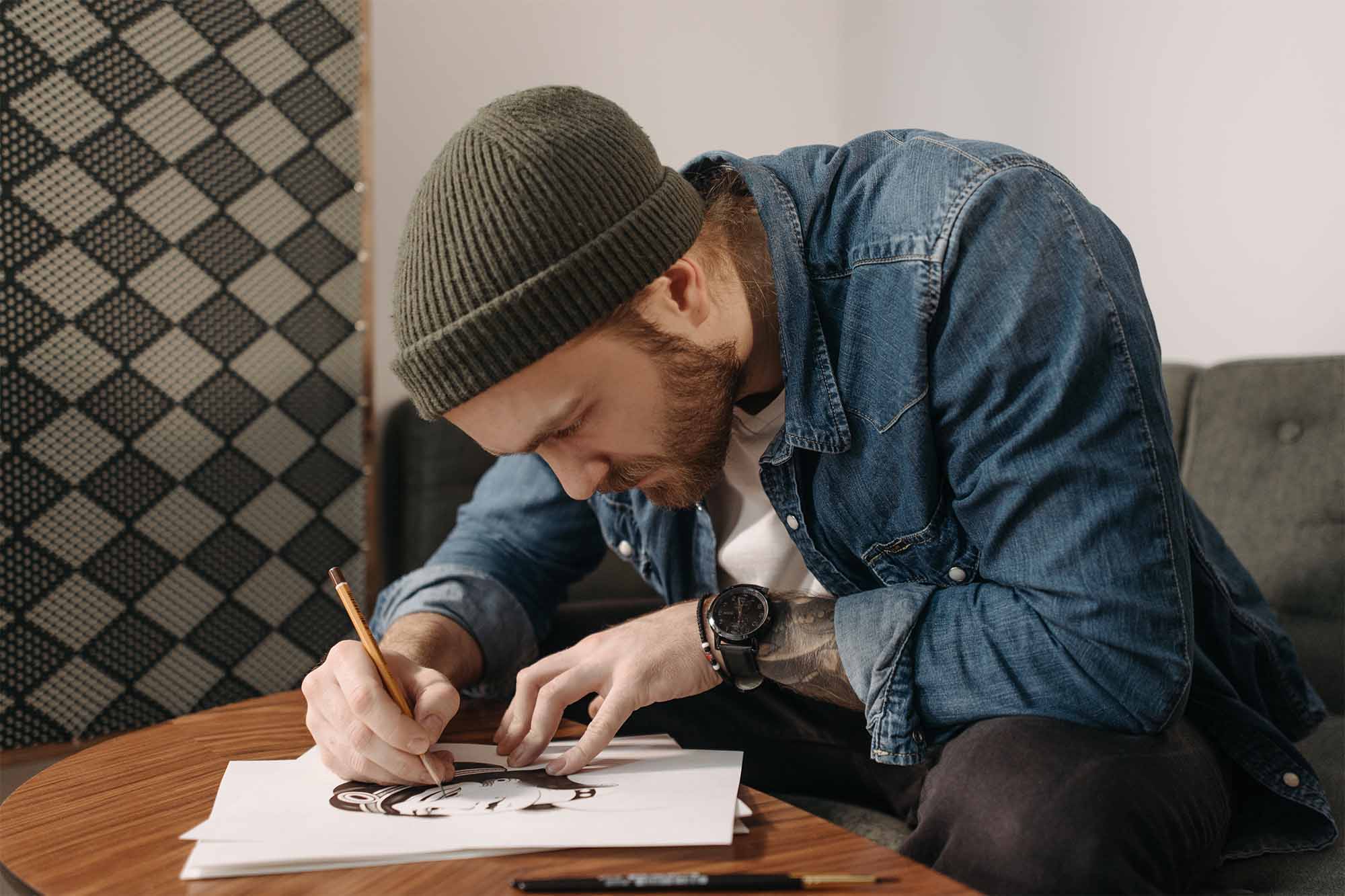 Bearded-man sitting on a couch, slouched over and drawing on an EtchPad
