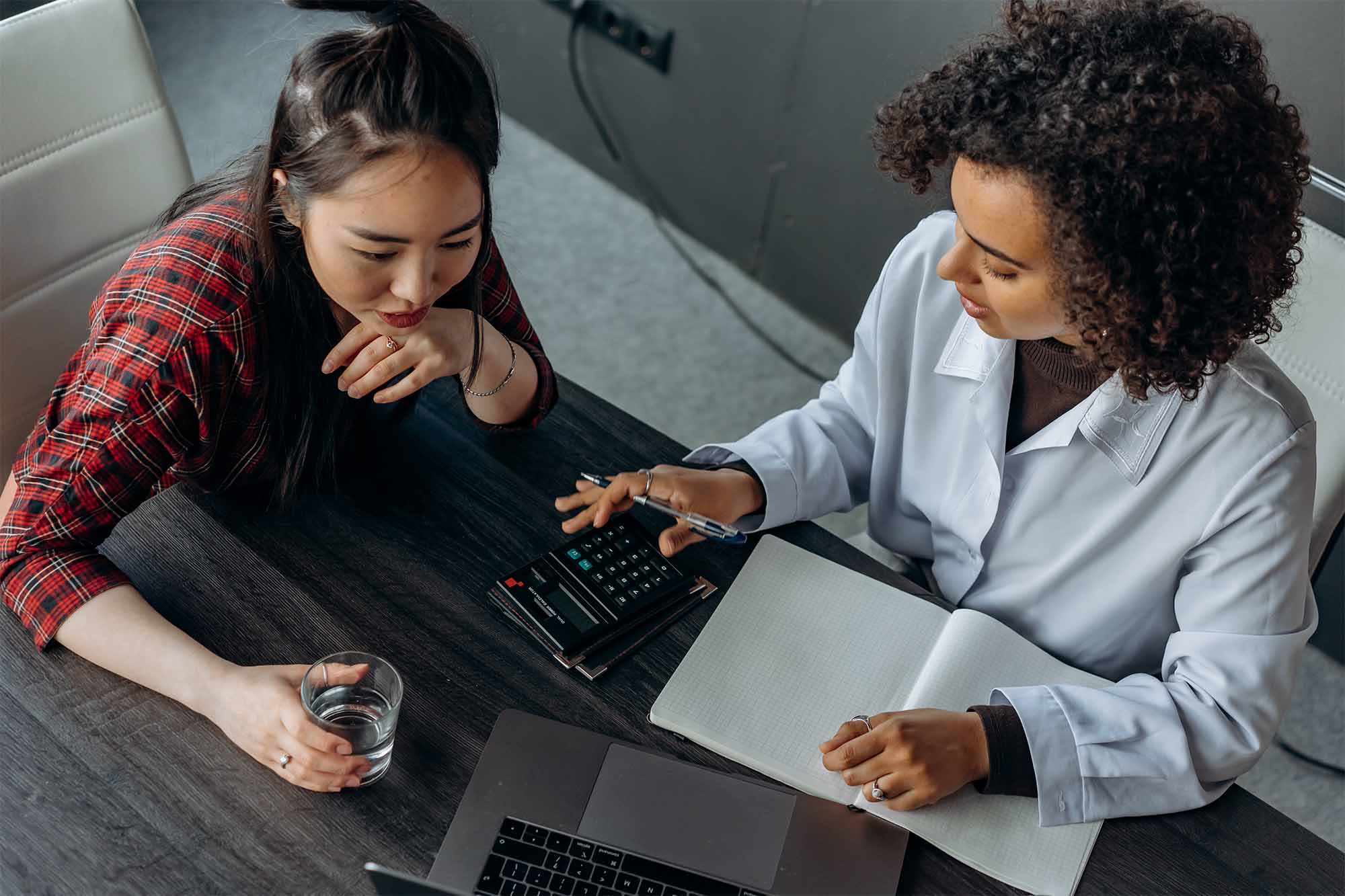Two women discussing business with their productivity devices on hand